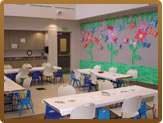 Room with tables and chairs out and construction paper flowers on the wall